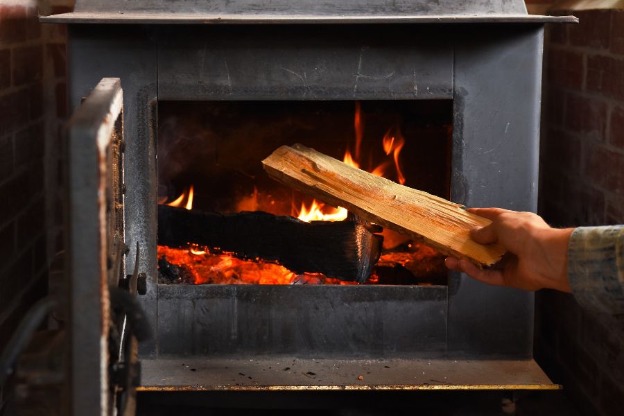 putting firewood in a wood stove